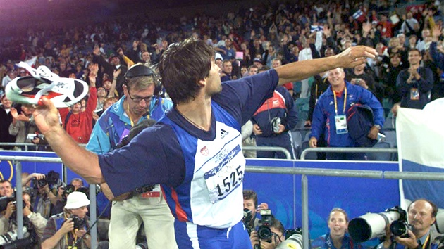 Jan �elezný v euforii po vít�zném závod� v Sydney, který mu p�inesl t�etí olympijské zlato, hází tretry nad�eným divák�m.
