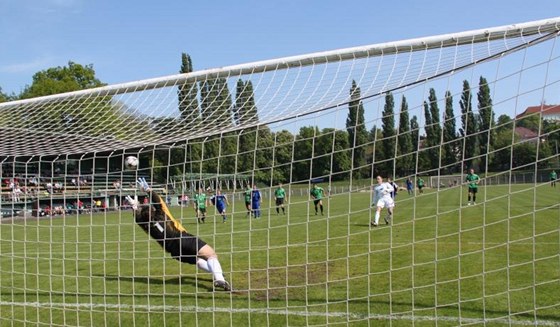 SOUBOJ BRANKÁ. Chomutovský Zako (v bílém) stílí penaltu na abu z Vltavínu, který smr vystihl, ale na ránu do ibenice nedosáhl.