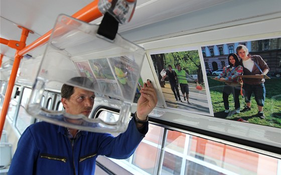 Pracovník Dopravního podniku umisuje tablo do tramvaje. 