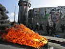 Hoící pneumatika ped portrétem nejznámjího palestinského lídra Jásira Arafata