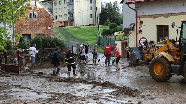Obyvatelé obce Úlice a hasii odklízejí nánosy bahna po prudké bouce.