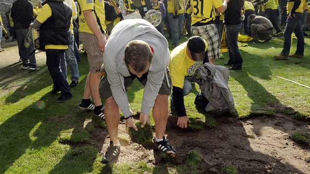 NA PAMÁTKU. Fanouci Dortmundu si berou jako suvenýry dom kusy trávníku ze stadionu, na kterém jejich tým oslavil titul.