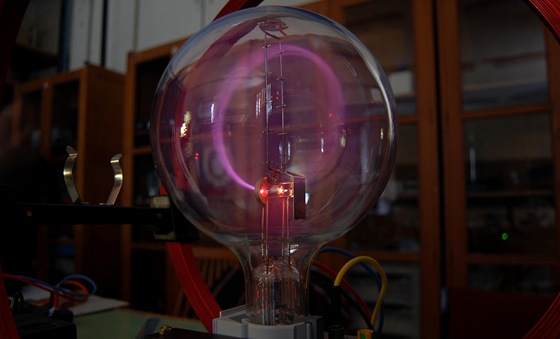 Proud elektron ohnutý v magnetickém poli do kruhu. Svtlo vydávají atomy plynu, které nabudí do nich naráející elektrony