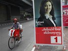 Zastánce opoziní Strany Thajc projídí kolem plakátu, na nm je éfka strany