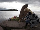 Norská dívka zapaluje svíku u památníku obtí stelby na protilehlém ostrov...
