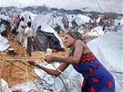 Žena staví provizorní přístřešek v jednom z uprchlických táborů na předměstí