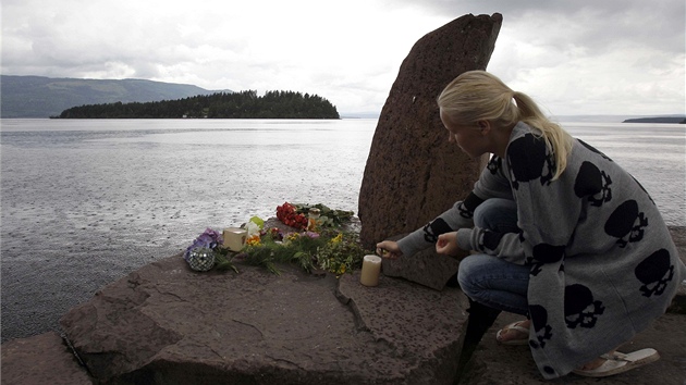 Norská dívka zapaluje svíku u památníku obtí stelby na protilehlém ostrov...