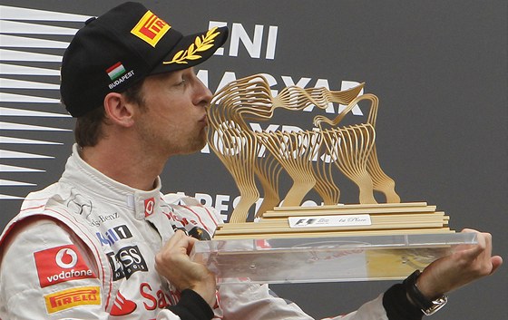 Spokojený Jenson Button líbá trofej pro vítze Velké ceny Maarska.