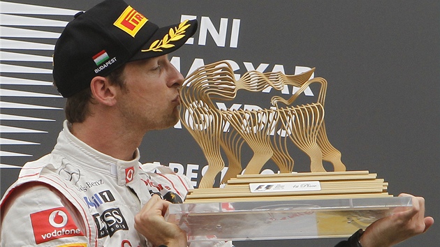 Spokojený Jenson Button líbá trofej pro vítze Velké ceny Maarska.