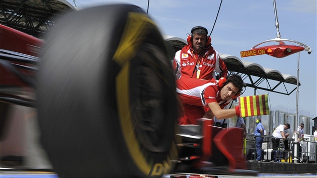 STOP! Mechanici Ferrari zastavují Fernanda Alonsa pi píjezdu do box.