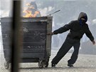 Maskovaný mladík veze popelnici s hoícími odpadky v londýnské tvrti Hackney.
