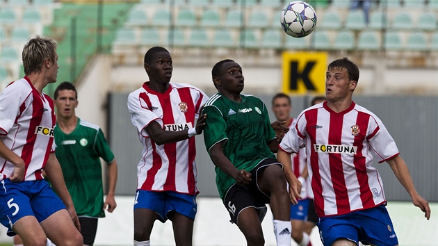 Patrick Onyango (v zeleném) z Mostu kontroluje mí� p�ed Fallem Laminnem z Brna.