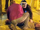 Policista s kolemjdoucím oetují starího zranného mue, kterého zranili