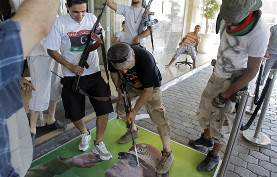 Libyjtí rebelové strhávají portréty a plakáty Muammara Kaddáfího. (23. srpna