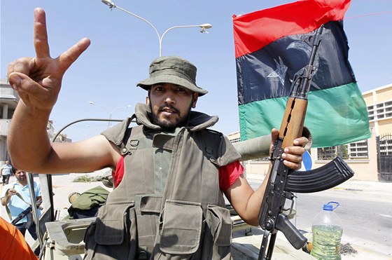 Rebel v Kaddáfího rezidenci ukazuje znak vítzství. (24. srpna 2011)