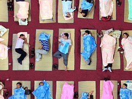 Rodie novopeených student spí na zemi tlocviny univerzity v ínském mst