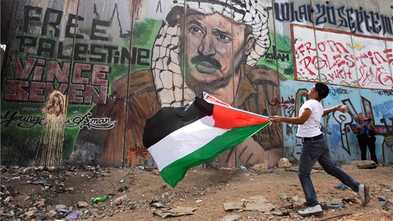 Palestinský mladík hází kamenem smrem k izraelskému území na hraniním pechodu Calandia.