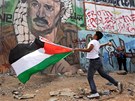 Palestinský mladík hází kamenem smrem k izraelskému území na hraniního