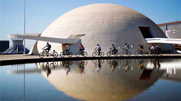 Skupinka cyklistů míjí proslulé muzeum v brazilském hlavním městě Brasílii. Budova vznikla podle návrhů nejslavnějšího brazilského architekta Oscara Niemeyera. (22. září 2011)