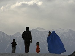Afghánská rodina kráí z kopce do metropole Kábulu. Matka v tradiní burce