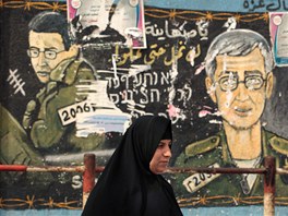Palestinka kráí v pásmu Gazy kolem zdi, na ní je vyobrazen izraelský voják
