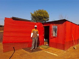 John Kwata u svého zářivě červeného domu v Thembelihle u Johannesburgu.