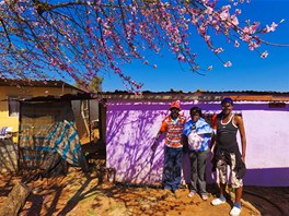 Amos Mkhuma stojí s dvěma slečnami před prodejnou nápojů u Johannesburgu.