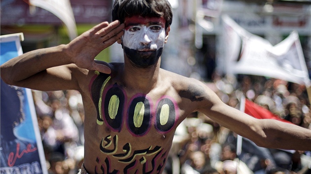 Demonstrant s namalovanou jemenskou vlajkou na tvái a arabsky napsaným heslem:
