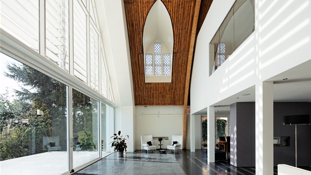 I do minimalistického interiéru pronikají původní stavební prvky jako jsou dřevěné nosné oblouky.