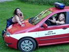 Dívky pózují na motorovém ebíku, na kapot hasiského auta nebo ve sluebním