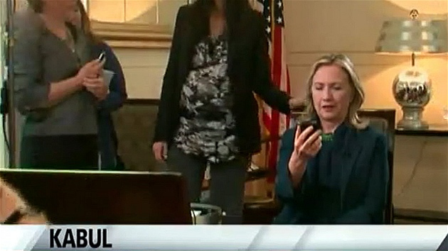 Pekvapená Clintonová se konsternovan dívá na mobilní telefon