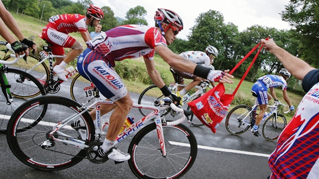 Ruský cyklista Alexandr Kolobněv během Tour de France přebírá tašku s