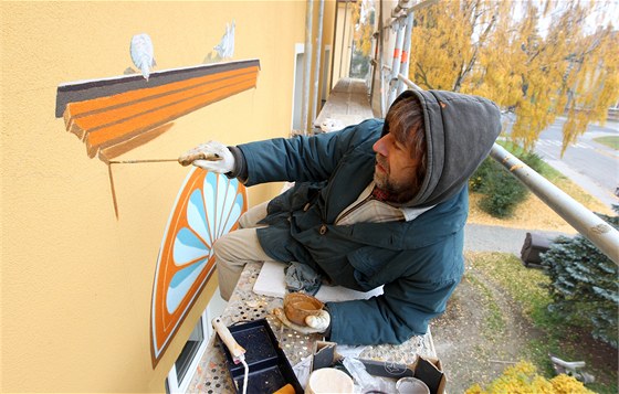 Výtvarník Milo Sláma penáí pvodní malby na novou fasádu.