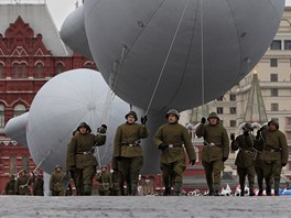 Rutí vojáci v dobových uniformách táhnou baráové balony, v pozadí historické