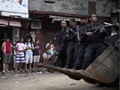 Obyvatelé slumu Rocinha sledují policisty, které veze chudinskou tvrtí...
