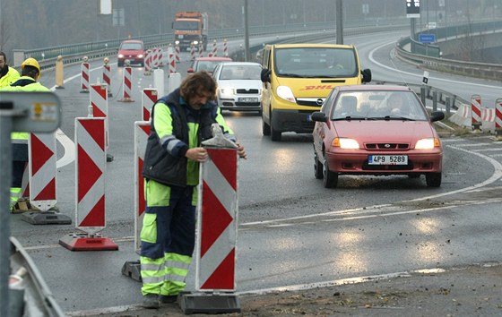 Dlníci pemisují provizorní dopravní znaení na práv oteveném posledním