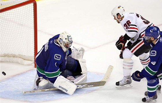 ZABIJÁK KOSATEK. Dave Bolland z Chicaga (v bílém) trápí Vancouver svými góly na led a mimo nj zase posmnými komentái.