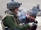 Malí Afghánci pozorují hlídkujícího nmeckého vojáka bhem pauzy na cigaretu....
