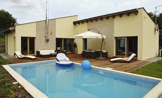 Vechny obytné místnosti jsou orientovány na rohovou devnou terasu s bazénem.