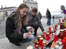 Dívky zapalují svíky u sochy TGM na Hradanském námstí v Praze. (23. prosince
