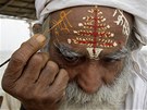 Ind si na behu eky Gangy kreslí na elo nápis Veselé Vánoce v hindtin.