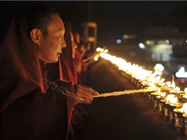 Tibetský buddhistický mnich zapaluje máslovou lampu v chrámu Dokang ve Lhase.