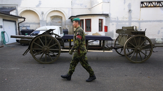 Voják v areálu kasáren hradní stráe prochází kolem historické lafety, která