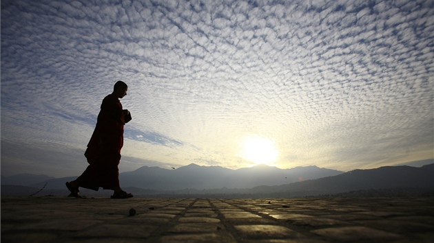 Buddhistický mnich krá�í p�i západu slunce po st�e�e klá�tera Svajabunát v