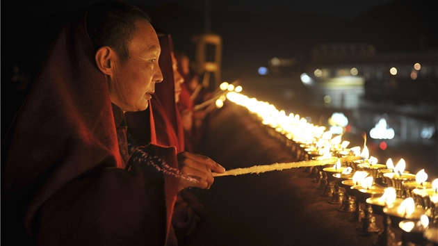 Tibetský buddhistický mnich zapaluje máslovou lampu v chrámu Dokang ve Lhase.