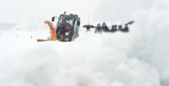 Snný pluh následovaný chodci odklízí sníh z cesty v St. Martin nedaleko rakouského Loferu. (8. ledna 2012)