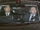 Makoto Hirata (schovávající se postava uprosted vozu) v policejním aut....