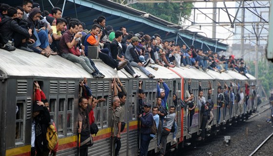 Takhle vypadá klasický indonéský vlak, desítky lidí sedí na střeše, další visí