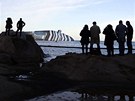 Turisté pozorují ásten potopený vrak lodi Costa Concordia u toskánského