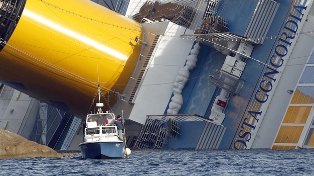 Policejní lun proplouvá kolem potopené lodi Costa Concordia. (22. ledna 2012)